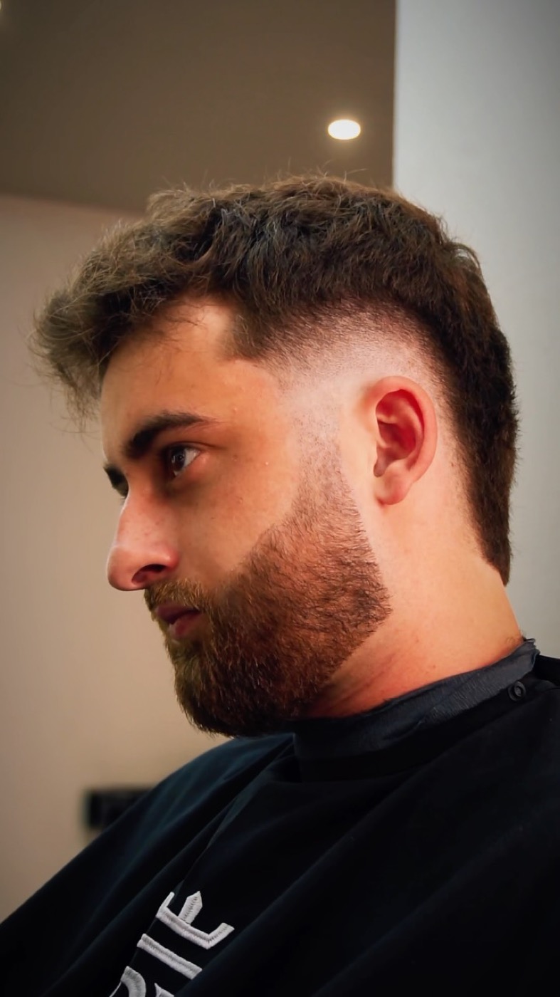 Homme coiffé avec un dessus texturé plein de mouvement, côtés dégradés et barbe dessinée, après passage chez BG Barbershop à Beynes